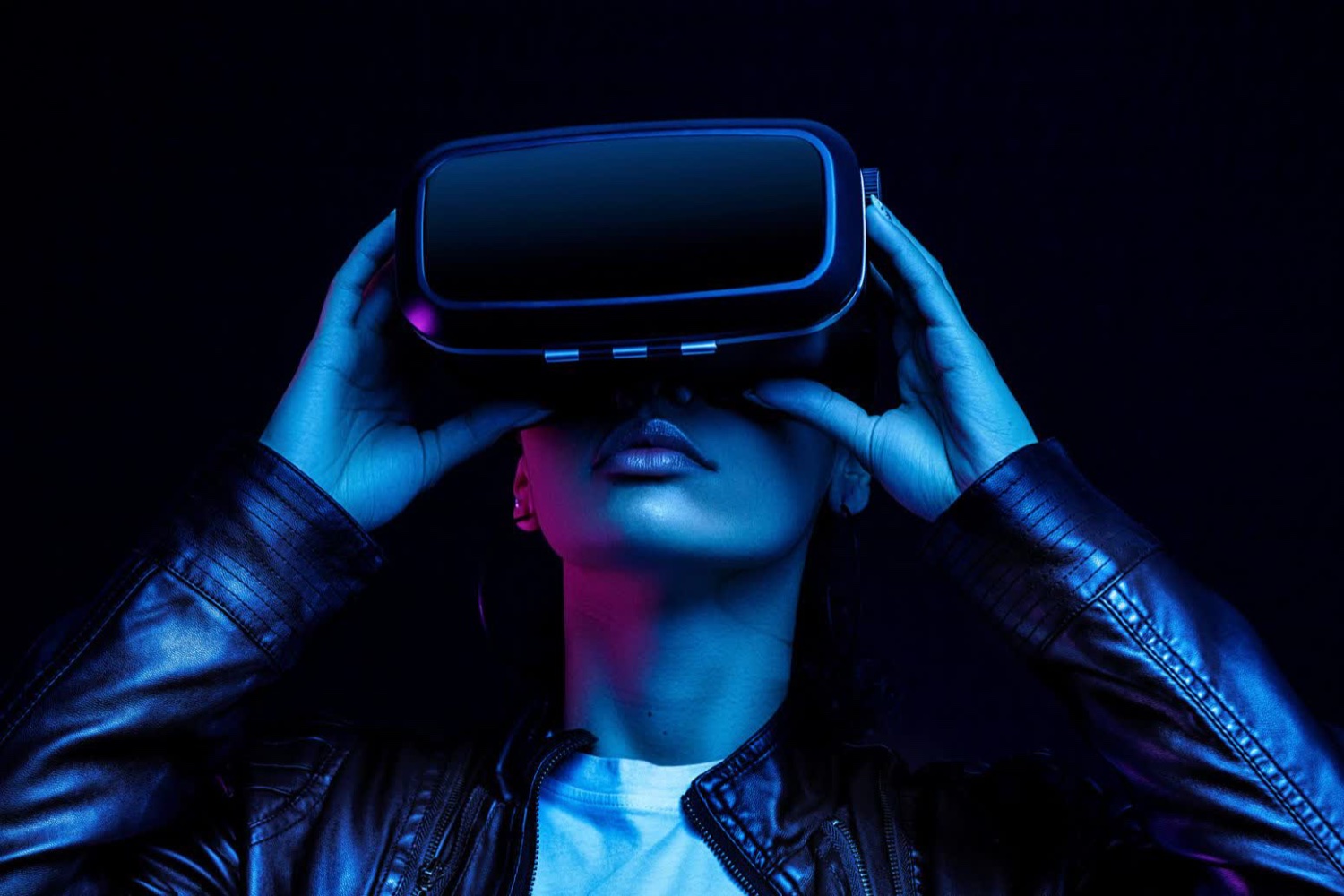 A person wearing a VR headset, lit in blue and purple neon against black - the ubiquitous stock photo