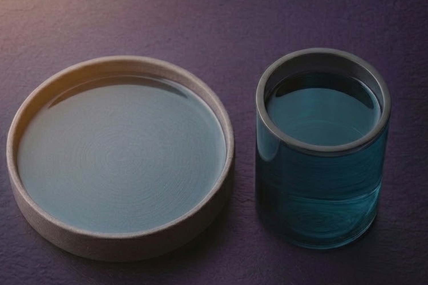 A wide shallow dish beside a narrow deep cup on a purple surface
